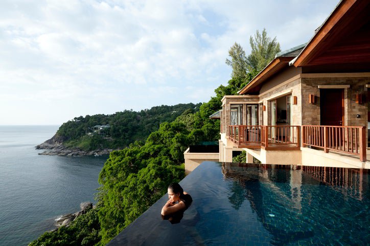 A woman in a pool at a luxury hotel overlooking the ocean.