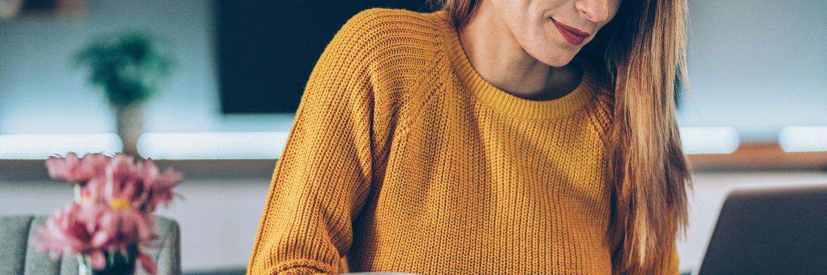 A woman at a desk looking at her computer and holding a credit card.