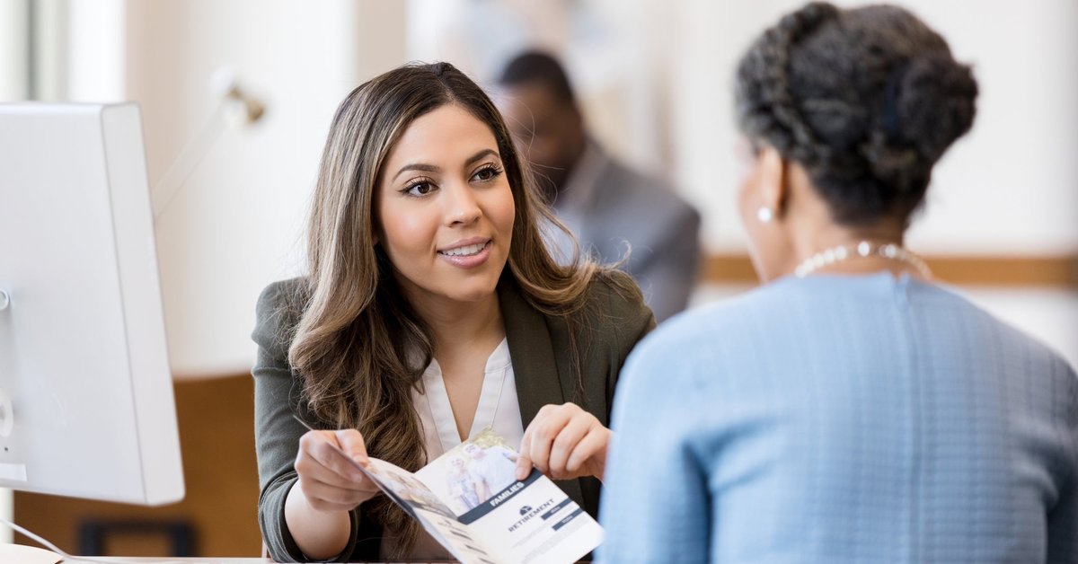 A bank manager helps a woman open up a new account.