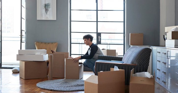 A woman packing moving boxes in her living room.
