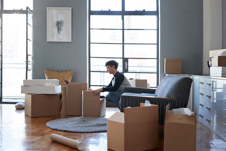 A woman packing moving boxes in her living room.