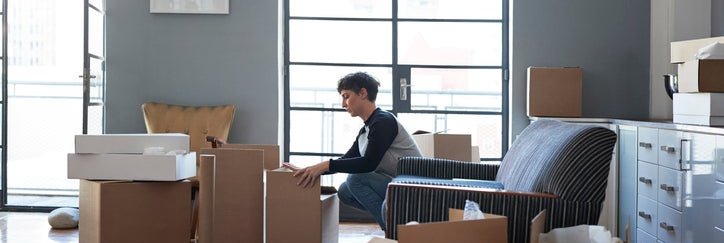 A woman packing moving boxes in her living room.