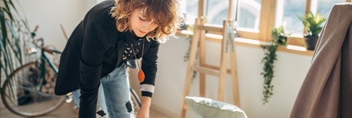 A woman packing moving boxes in a sunny apartment.