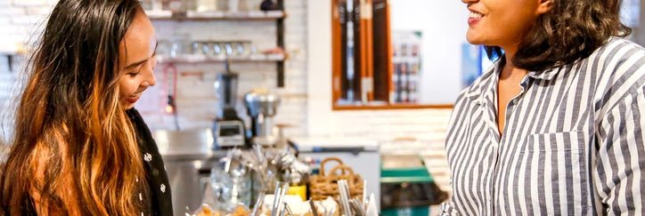 A smiling woman paying with a credit card at a restaurant checkout counter.