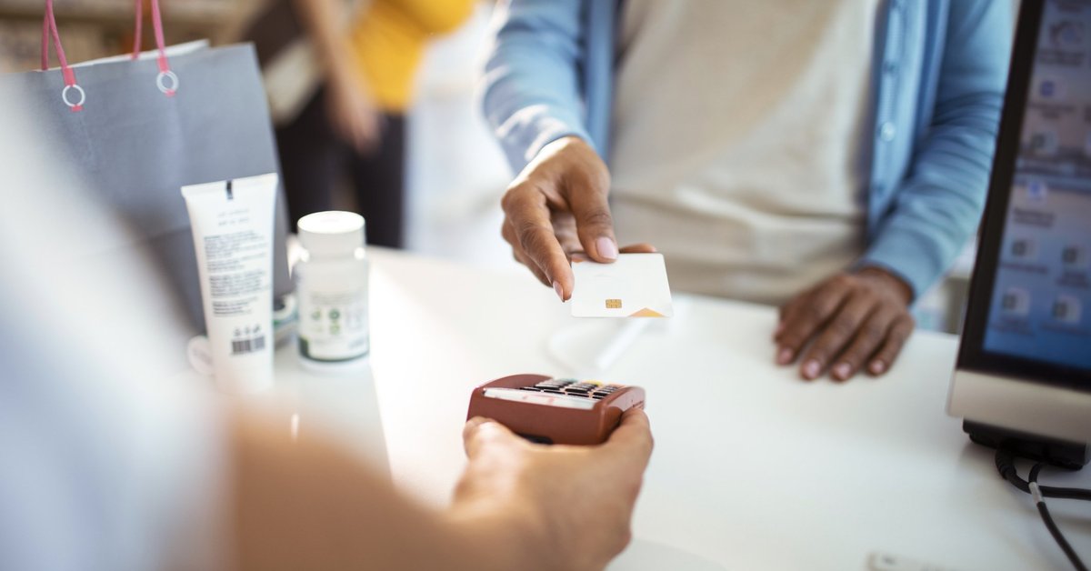 A woman holding her credit card up to the payment reader at the pharmacy.