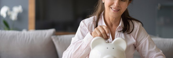 Woman putting coins into piggy bank