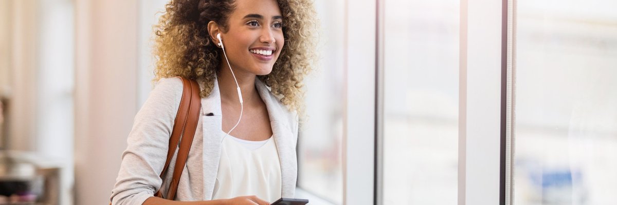 A woman smiling in an airport with her suitcase and passport.