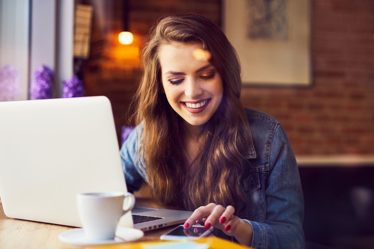 smiling woman holding coffee and computer