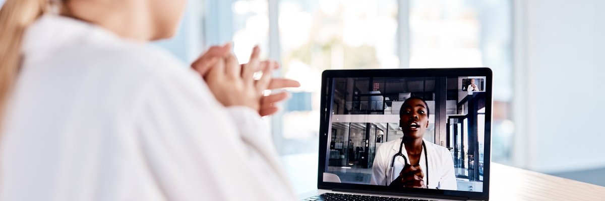 A woman at home speaking with her doctor on a laptop video call.
