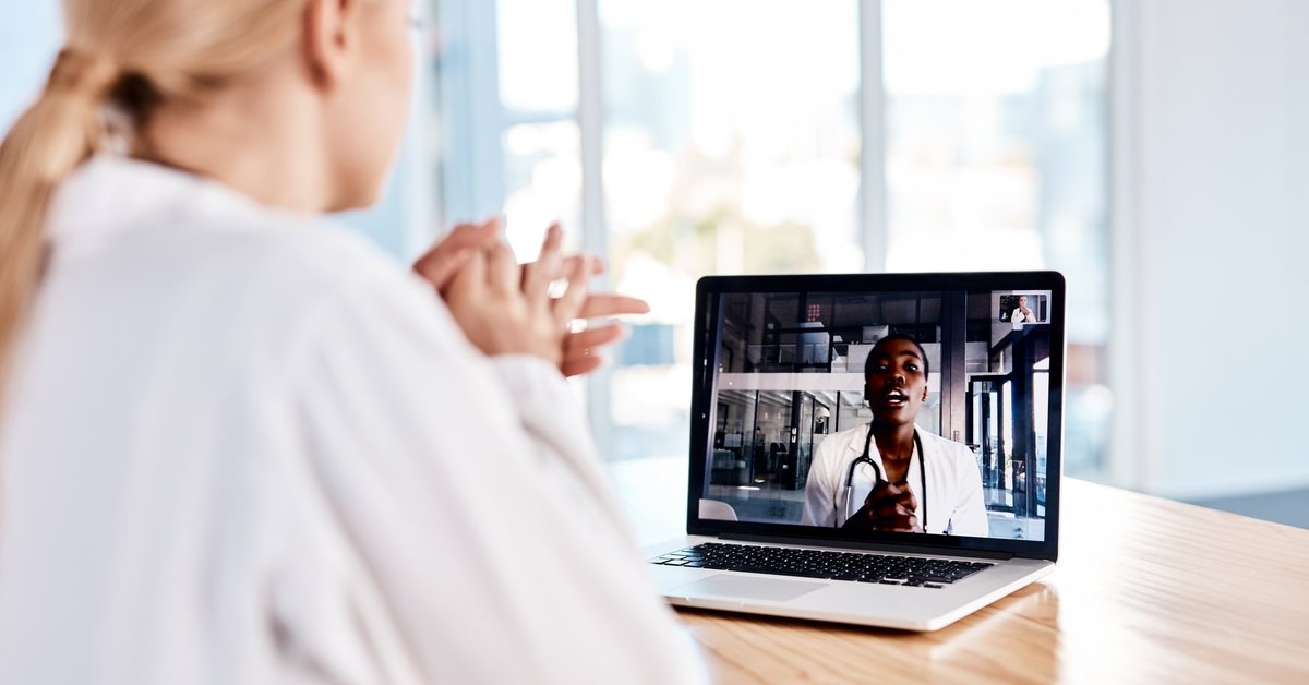 A woman at home speaking with her doctor on a laptop video call.
