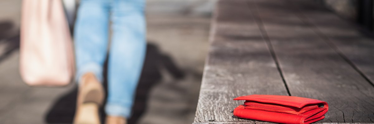 woman walking away from bench with wallet sitting on it
