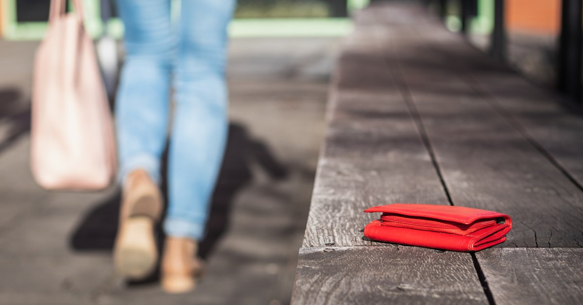 woman walking away from bench with wallet sitting on it