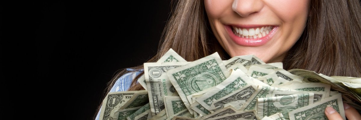 woman smiling and holding a large pile of cash