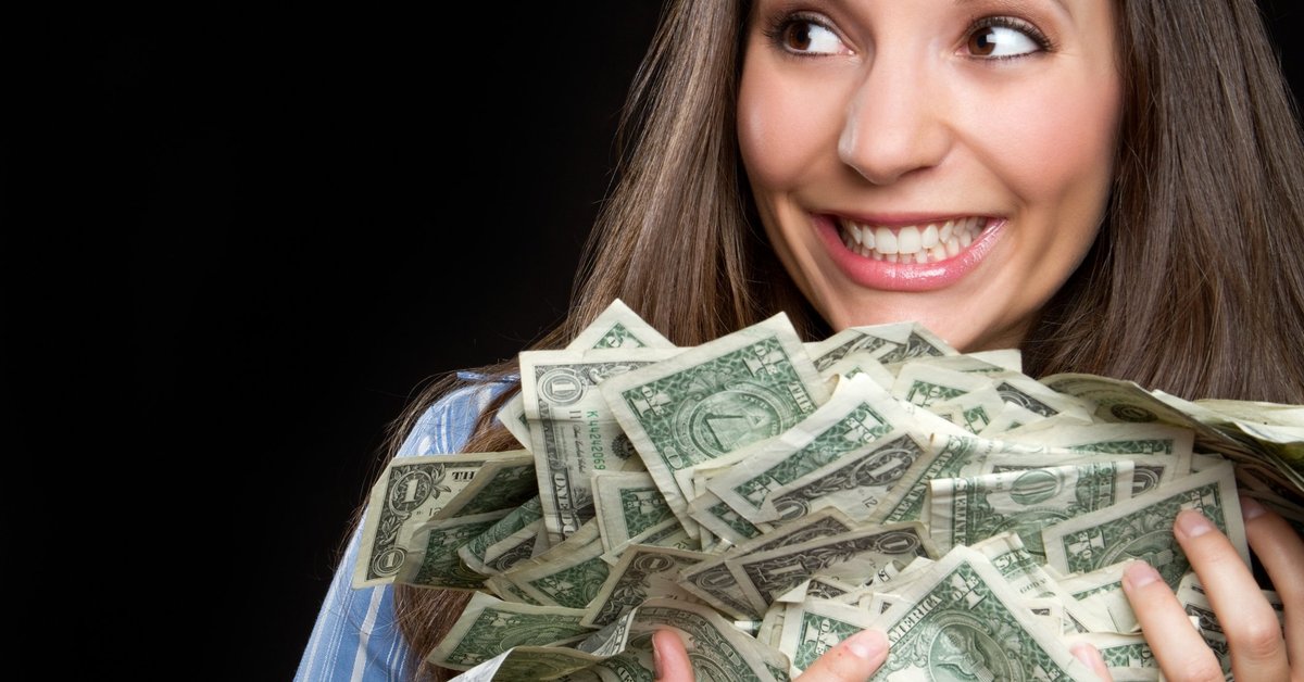 woman smiling and holding a large pile of cash