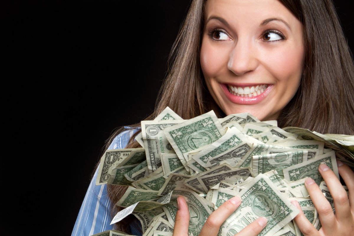 woman smiling and holding a large pile of cash