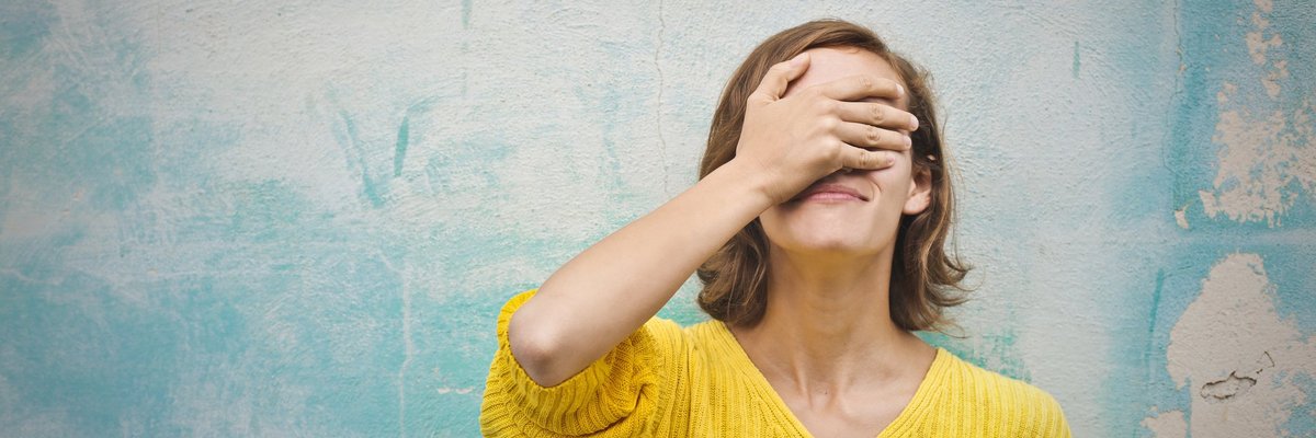 A young woman with her hand over face in regret.