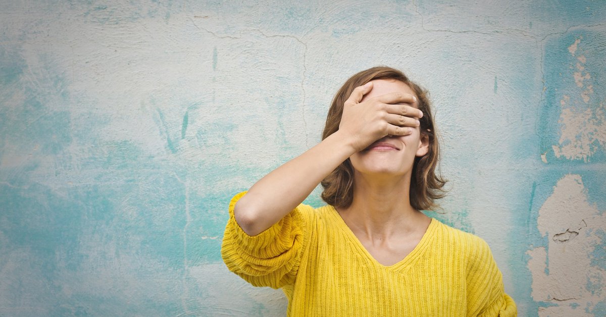 A young woman with her hand over face in regret.