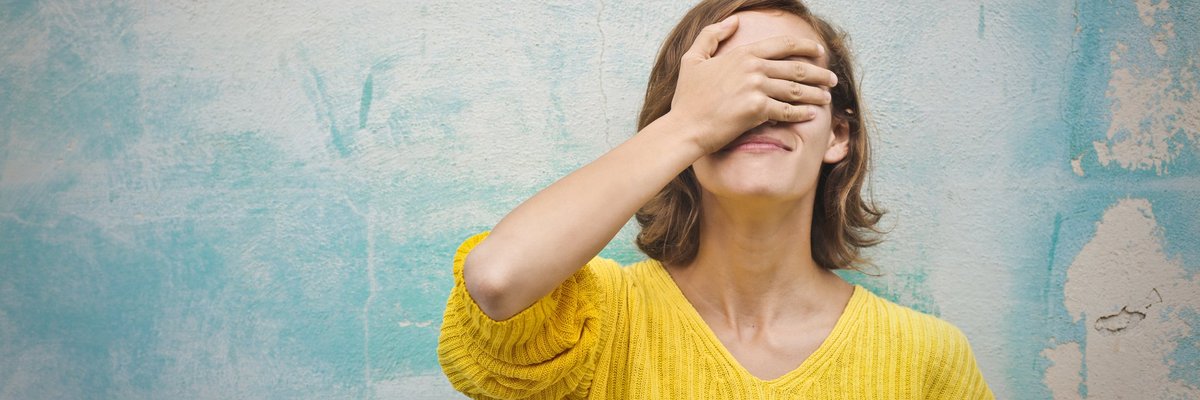 A young woman with her hand over face in regret.