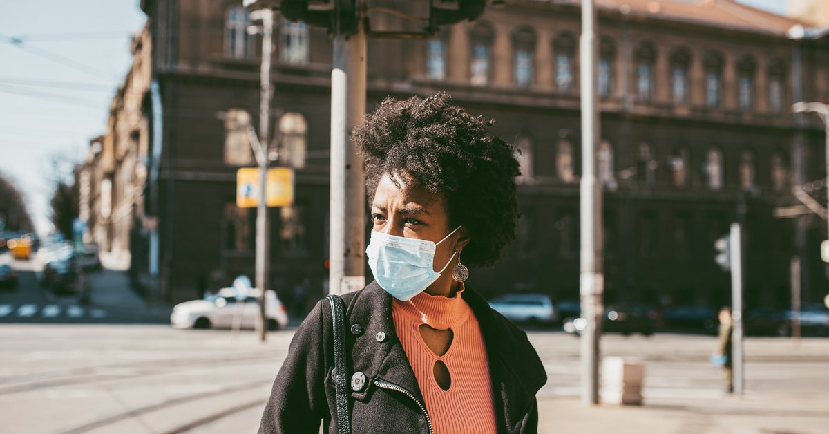 A woman wearing a medical mask walking down the street.