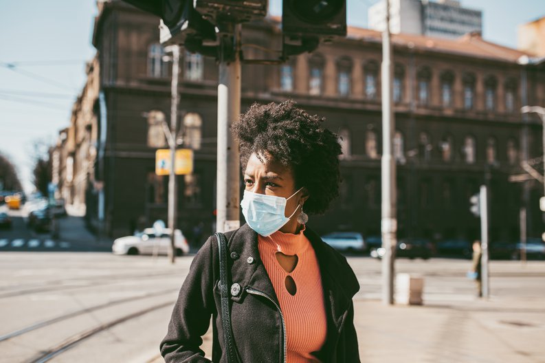 A woman wearing a medical mask walking down the street.