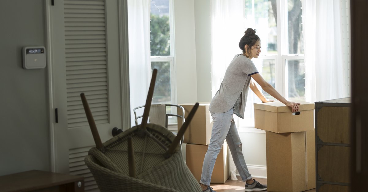 A woman looking unsure while moving boxes into a new house.