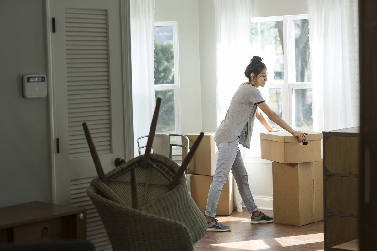 A woman looking unsure while moving boxes into a new house.