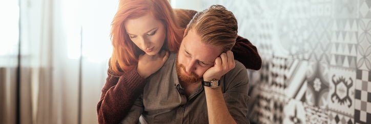 A worried couple looks at paperwork and a laptop.