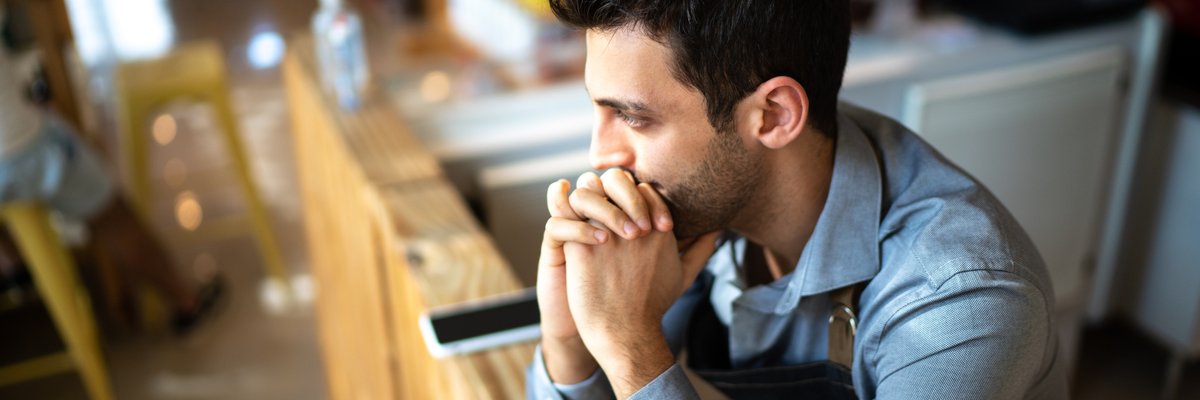 A worried person in an office leaning their chin on their hands.