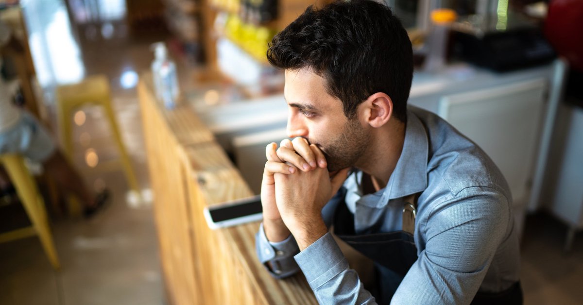 A worried person in an office leaning their chin on their hands.