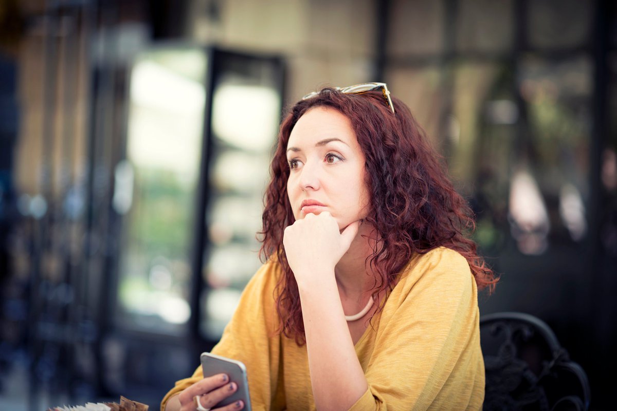 A worried person sitting with their chin resting on their hand and staring off into the distance.