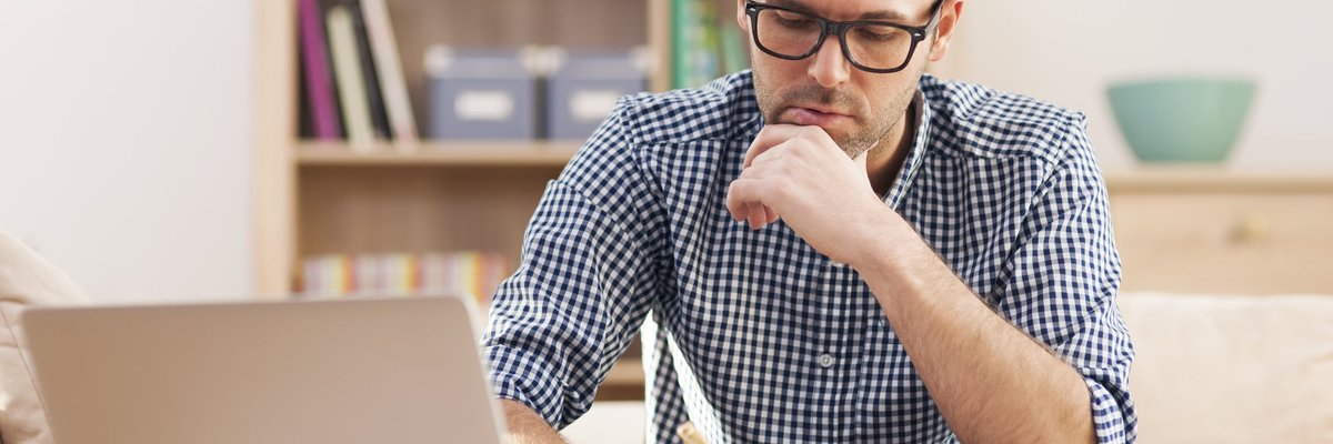 Man at laptop holding pen
