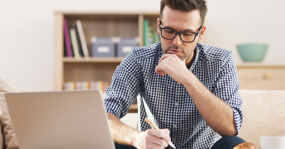 Man at laptop holding pen
