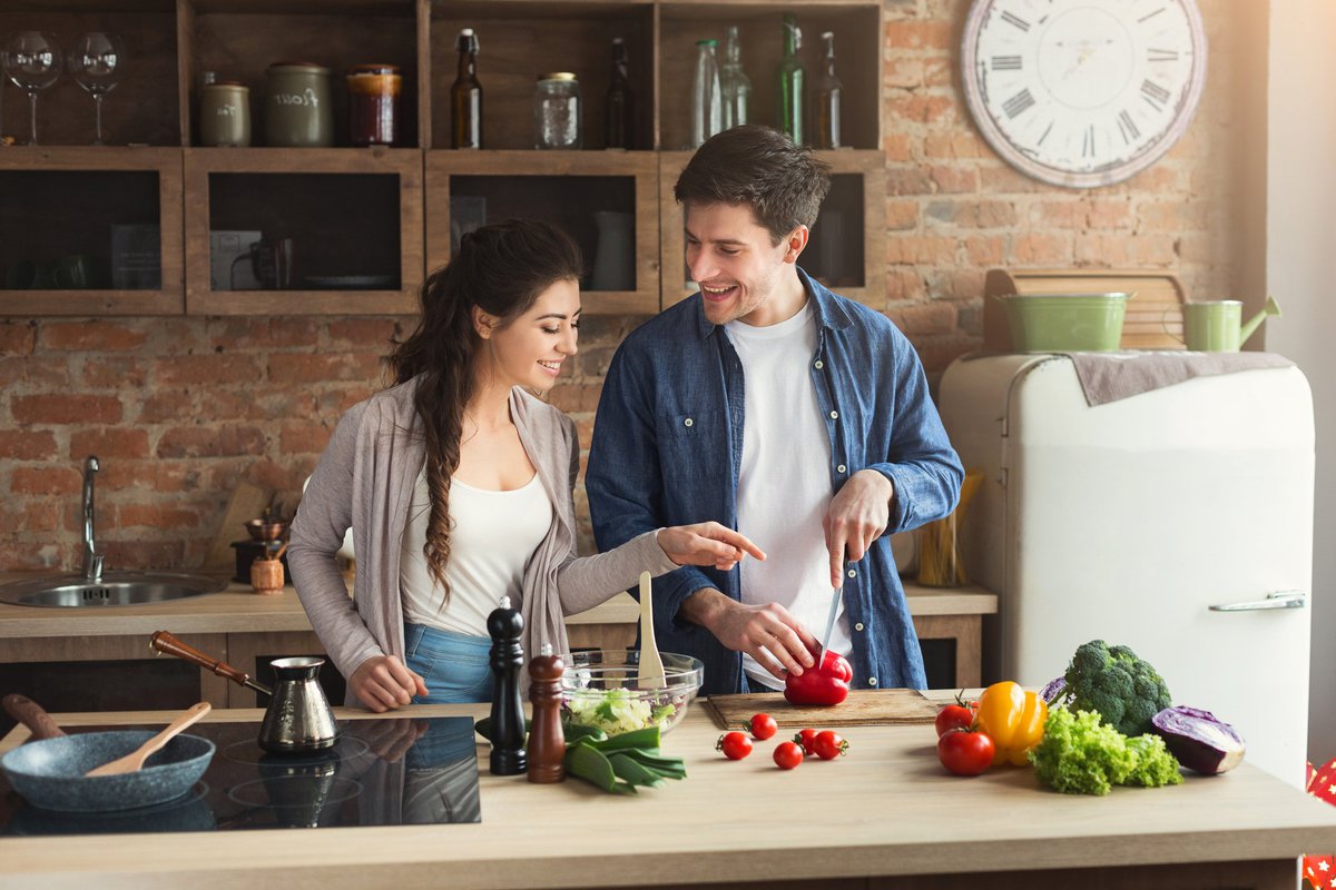 Smiling young couple cooking in kitchen
