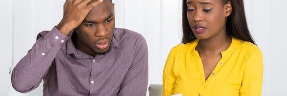 young couple looking at paper with worried faces