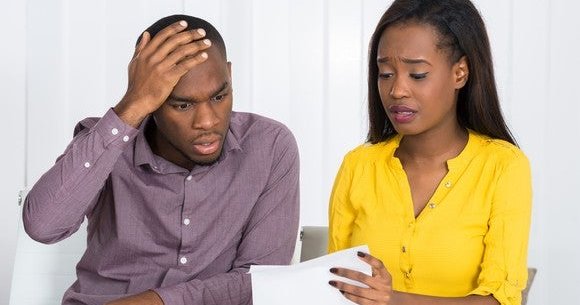 young couple looking at paper with worried faces