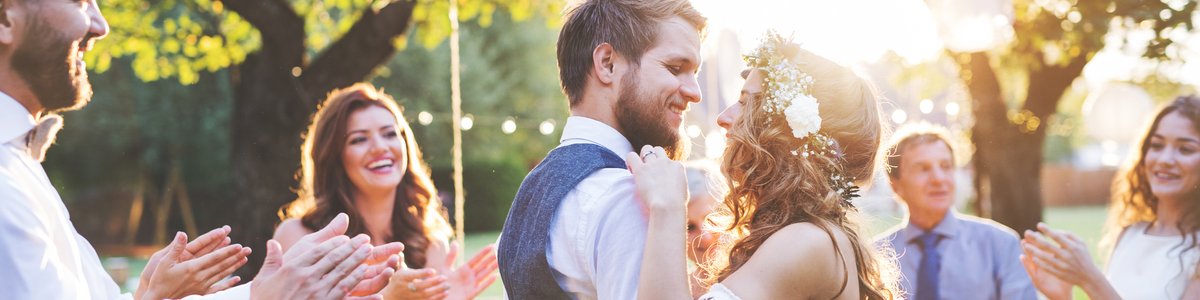 young bride and groom hugging in a backyard surrounded by friends