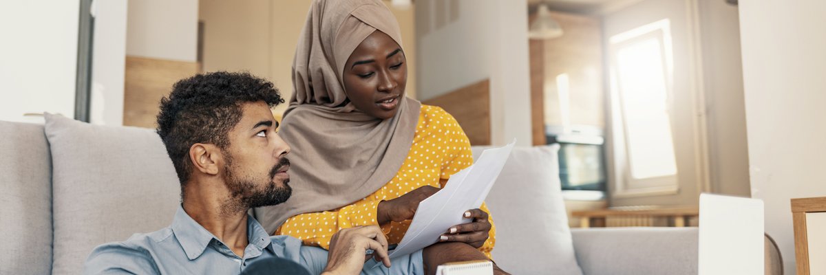 Two people looking over their bills while sitting on their living room couch.