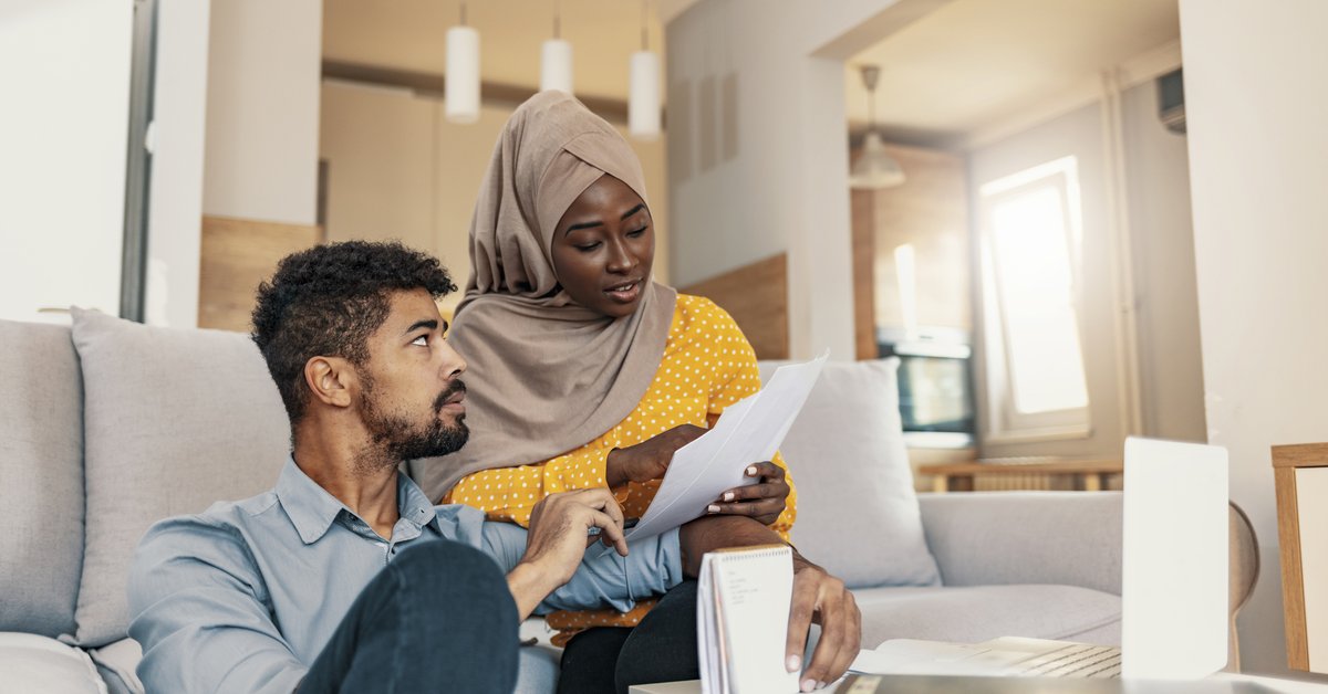 Two people looking over their bills while sitting on their living room couch.
