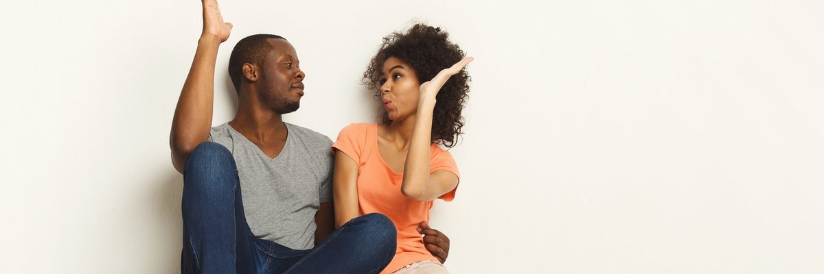 young man and woman sitting next to each other on the floor and giving each other a high five.