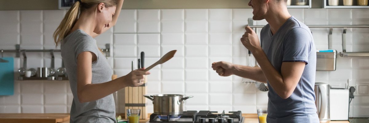 young man and woman smiling and dancing in kitchen