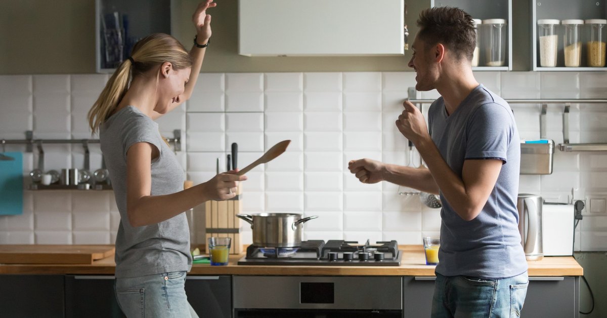 young man and woman smiling and dancing in kitchen