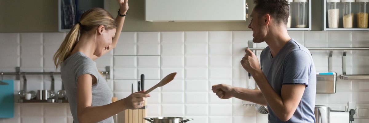 young man and woman smiling and dancing in kitchen