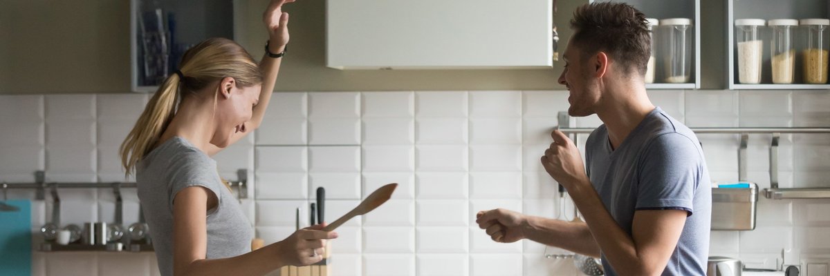 young man and woman smiling and dancing in kitchen -- couple celebrating happy
