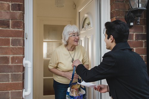 young man delivering groceries to senior woman.