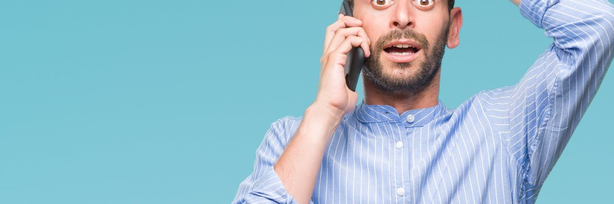 young man holding cellphone to his ear and holding his hand to his forehead like he made a mistake