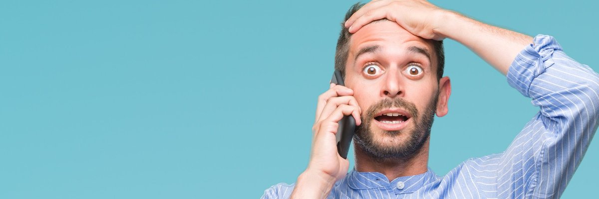 young man holding cellphone to his ear and holding his hand to his forehead like he made a mistake