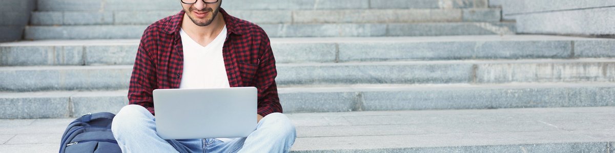 Young man on laptop sitting on steps