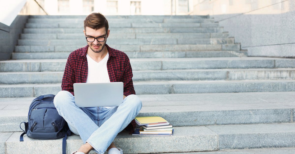Young man on laptop sitting on steps