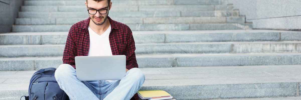 Young man on laptop sitting on steps