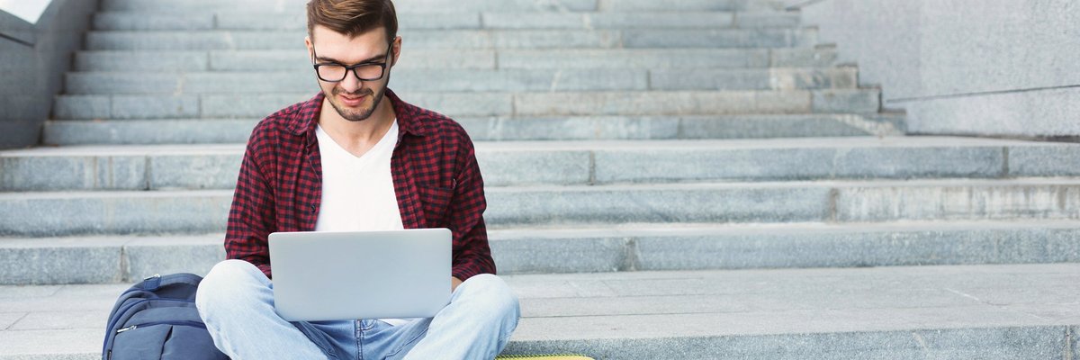 Young man on laptop sitting on steps
